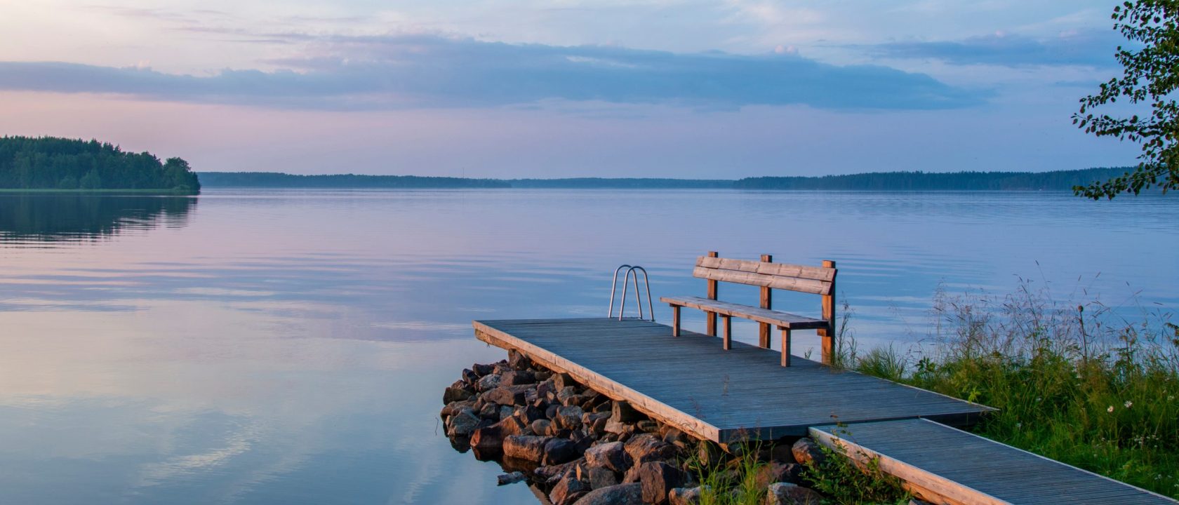 Tyyni järvi, sinivioletin sävyinen kesäillan auringonlasku, etualalla laituri